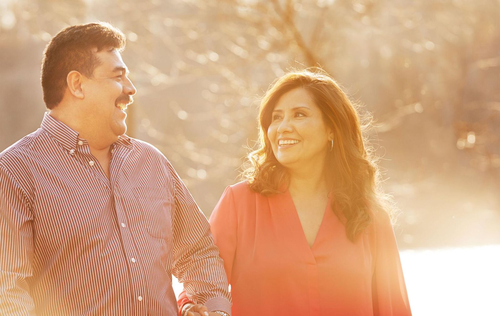 A smiling couple walking arm in arm in warm afternoon sunlight