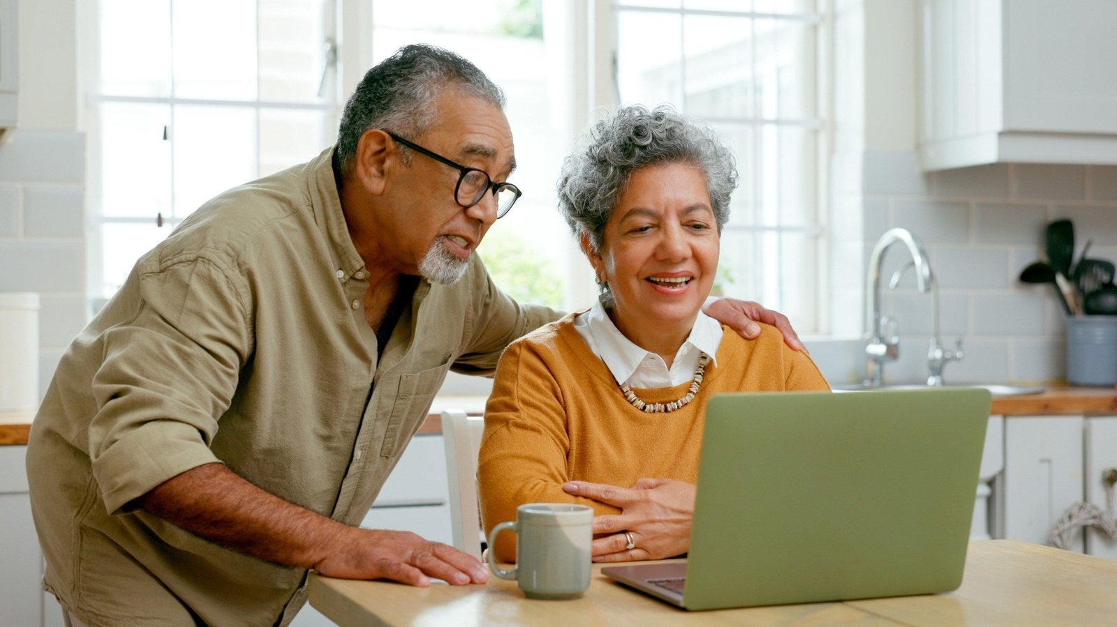 An older couple smiling as they look at a laptop together